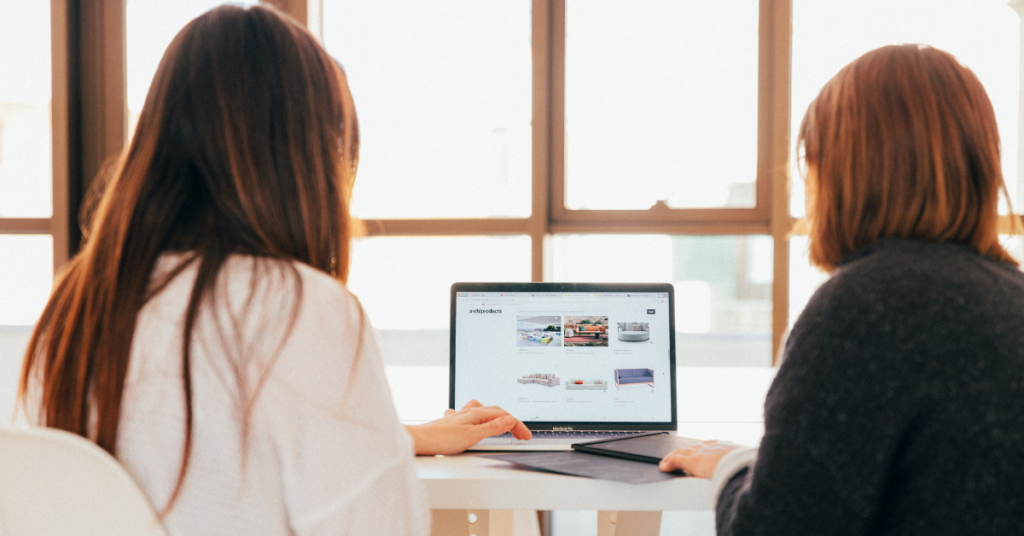 Two women looking at website content on a computer.