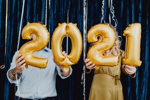 Two people holding up balloons reading 2021.